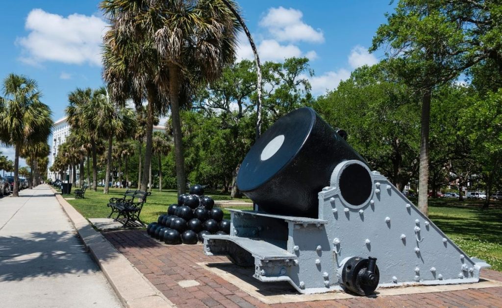 Battery Park with a canon monuments with cannonballs next to it with palm trees and blue skies, a Charleston South Carolina attraction