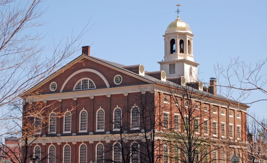 a large historic brick building in Boston with light blue skies and leafless trees