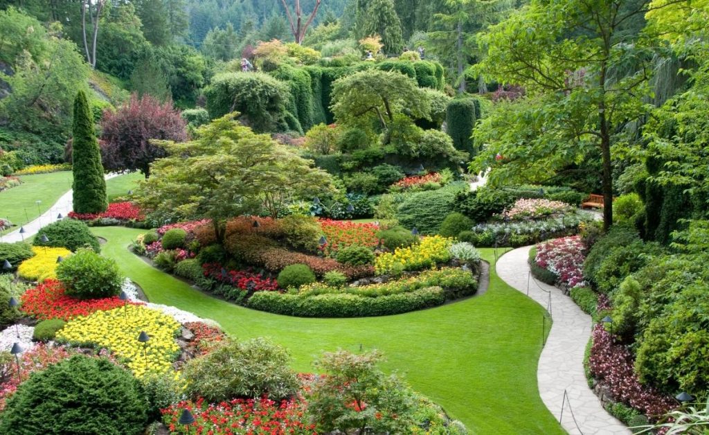 Butchart Gardens in Victoria, Canada with colorful flowers, green grass, trees, ad bushes