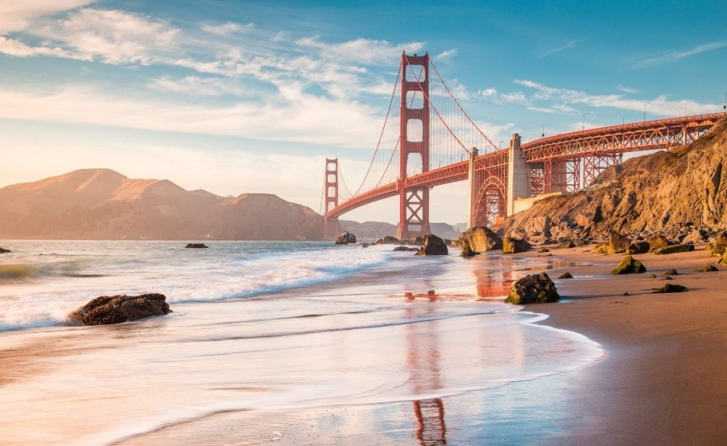 the Golden Gate bridge with mountains and water in the background to represent California trips to take