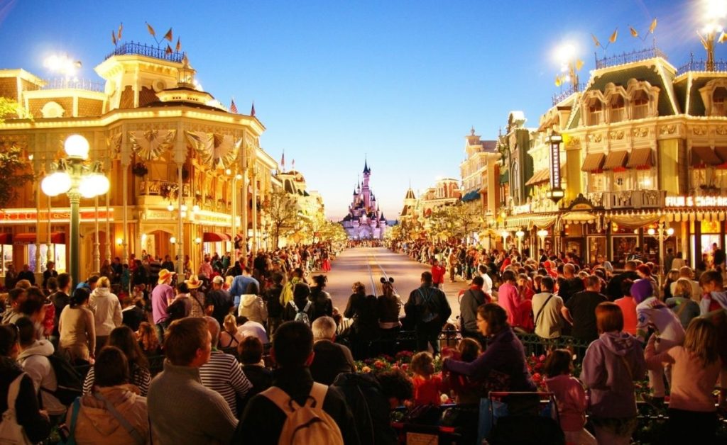 a street in Disneyland in Anaheim Orange County with people lined up in the street and the magic kingdom in the background 