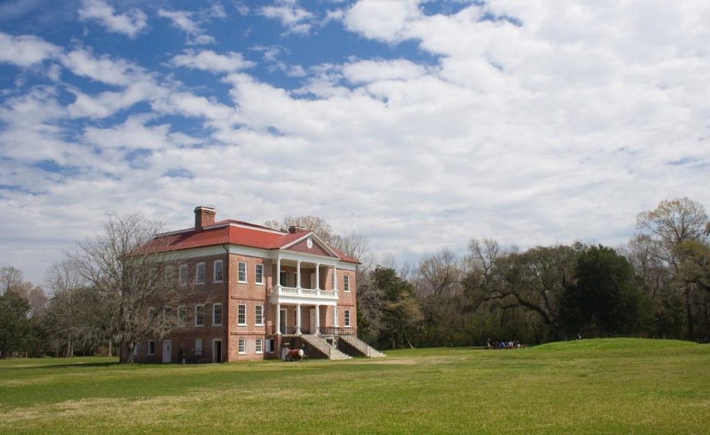 Drayton Hall Plantation with a brick exterior, cloudy skies and green grass. A Charleston South Carolina attraction