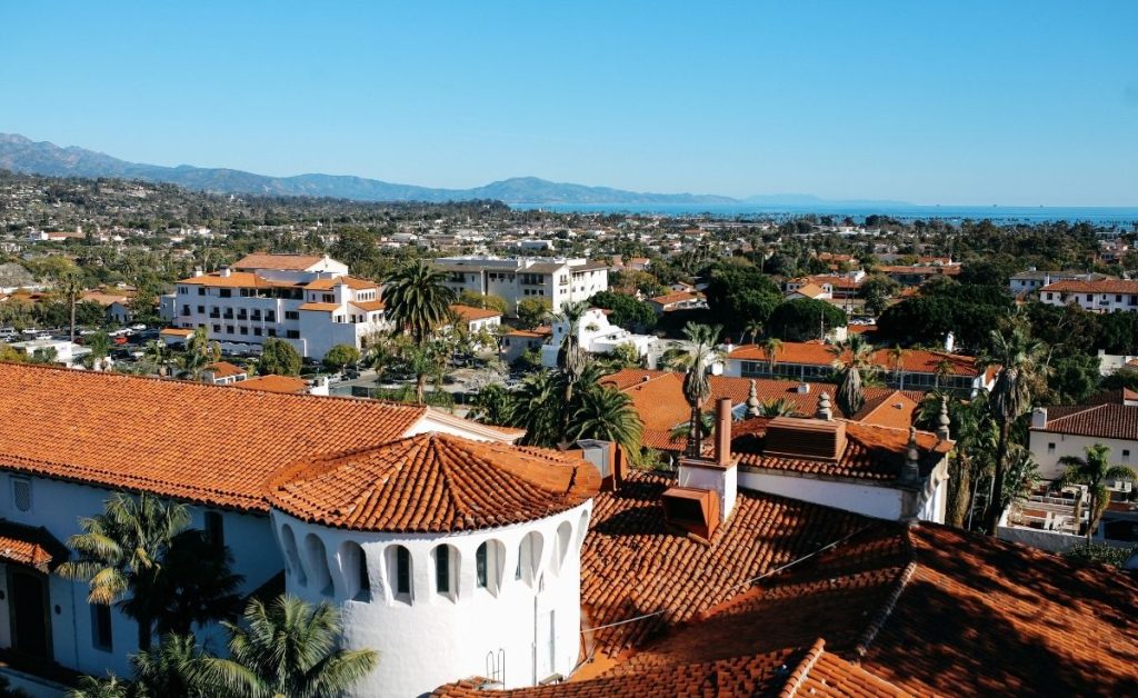 an aerial view of Santa Barbara, California with blue skies, white architecture with orange rooves.  
