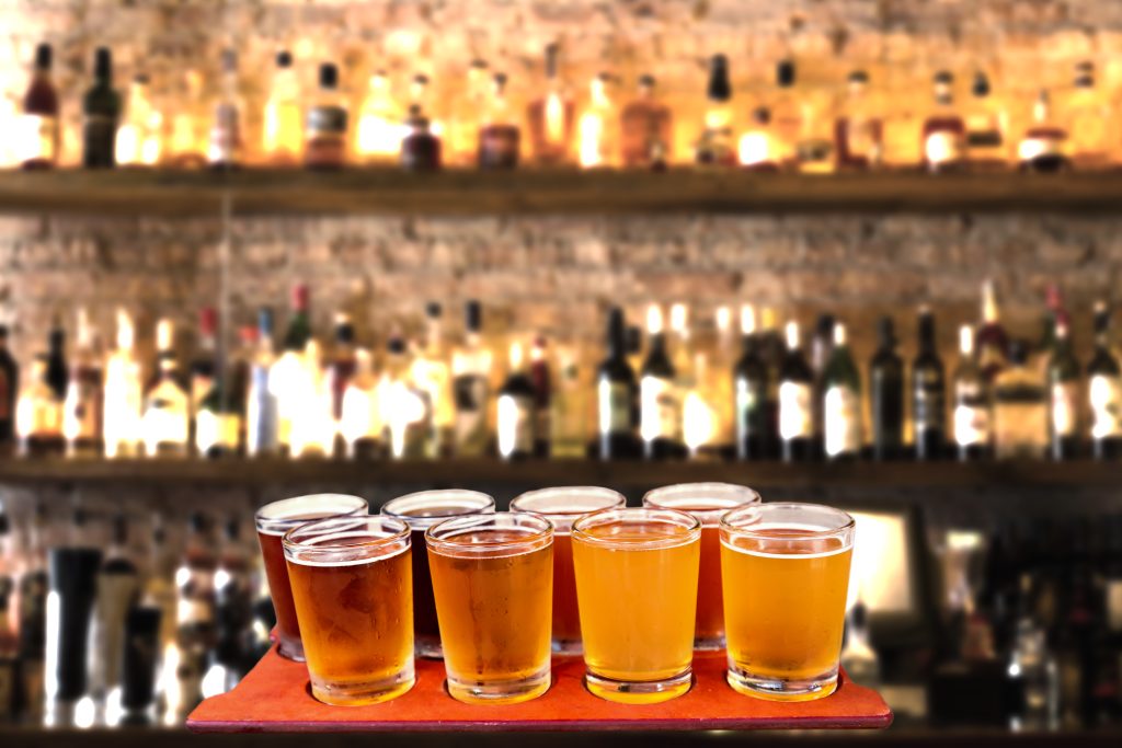 Beer flight of eight sampling glasses of craft beer on a bar countertop, an example of what you can drink at Charleston South Carolina breweries.