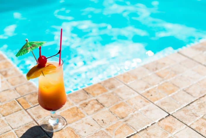 an easy mai tai cocktail sitting on the edge of a pool