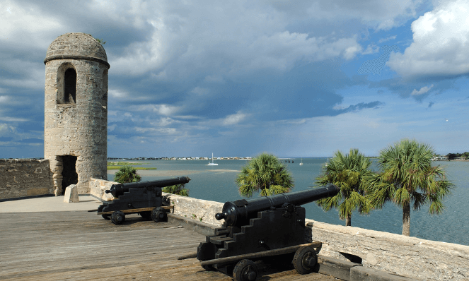 at the top of the Castillo De San Marcos Fort with old canons and blue water in front located in St. Augustine downtown