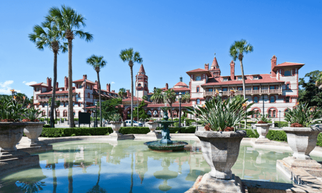 Flagler College one of the best Historic St. Augustine downtown attractions with blue skies, palm trees, and a water feature in the front of it