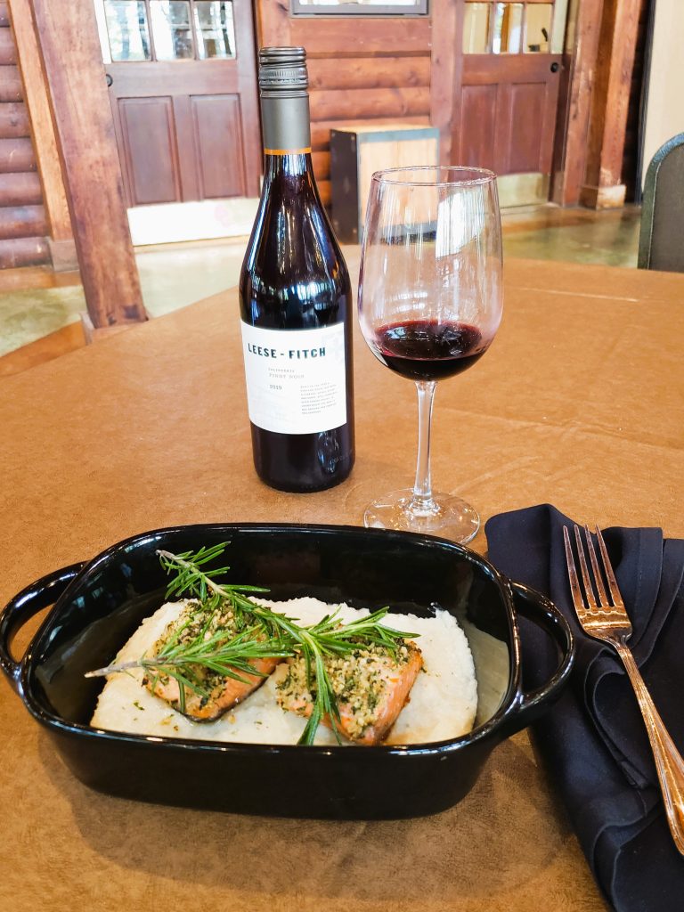 Chef AJ's Black Walnut crusted Trout over Boursin Grits with a glass of red wine © Jo Clark