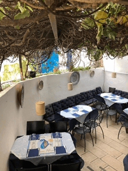 Il Posto Affianco a restaurant in Ostuni Italy with tables on a terrace with vines hanging over the trees