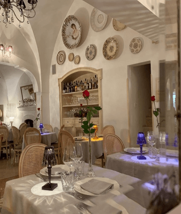 Osteria Piazetta Cattedrale a restaurant in Puglia with plates on the walls and white table cloth tables