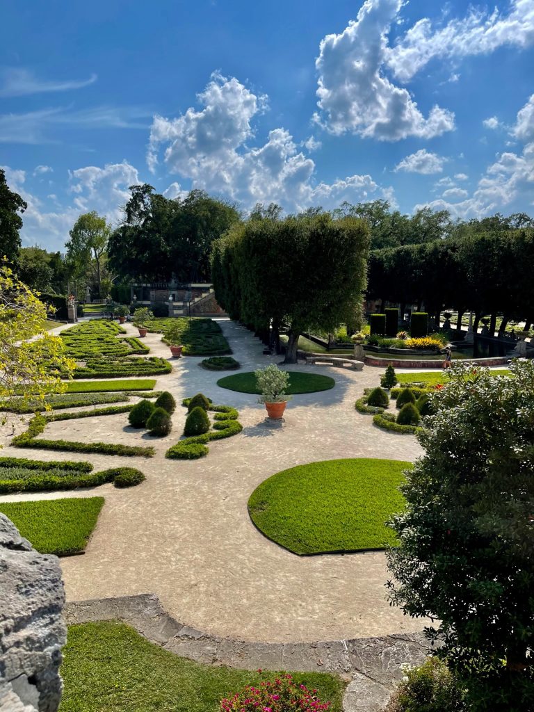 The Gardens of Vizcaya, one of the castles in Florida, are surrounded by pebbled walkways; includes shade trees and shrubbery