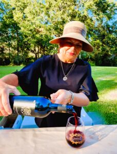 Woman in hat pouring sampling of red wine