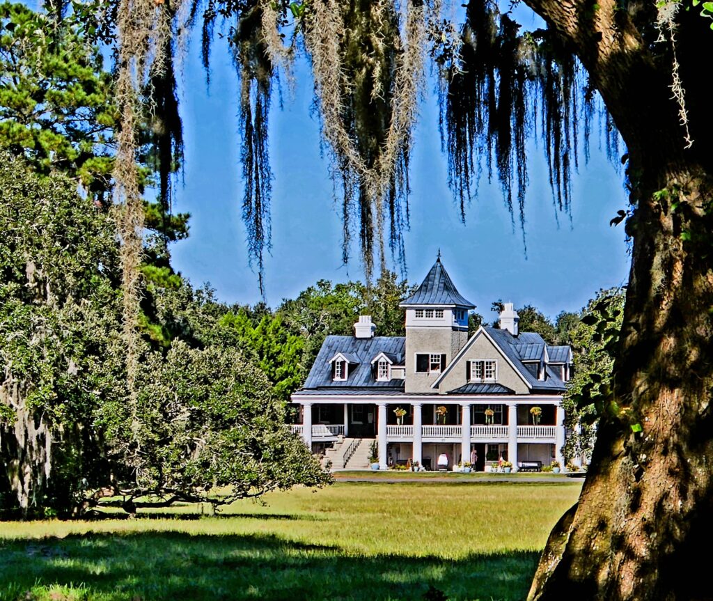 A view of the Magnolia Plantation and Gardens house across the lawn, seen through the moss-covered trees.
