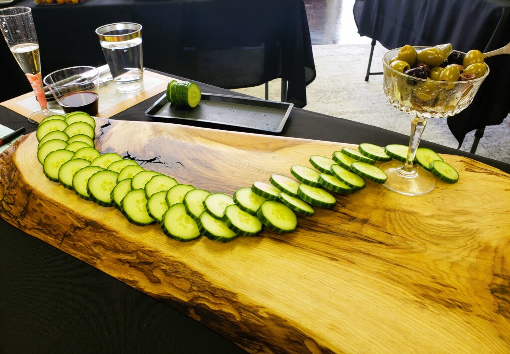 A curved line of cucumber slices down the length of the charcuterie board is the first step in learning how to make a charcuterie board 