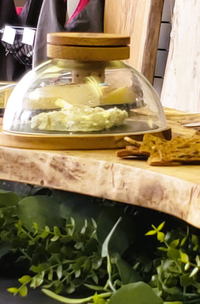 Cheese under a glass dome, with cherry wood smoke being piped into the dome