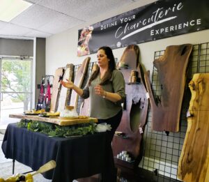 Marie, Nature's Platter owner, discussing charcuterie boards, with a large display of boards behind her