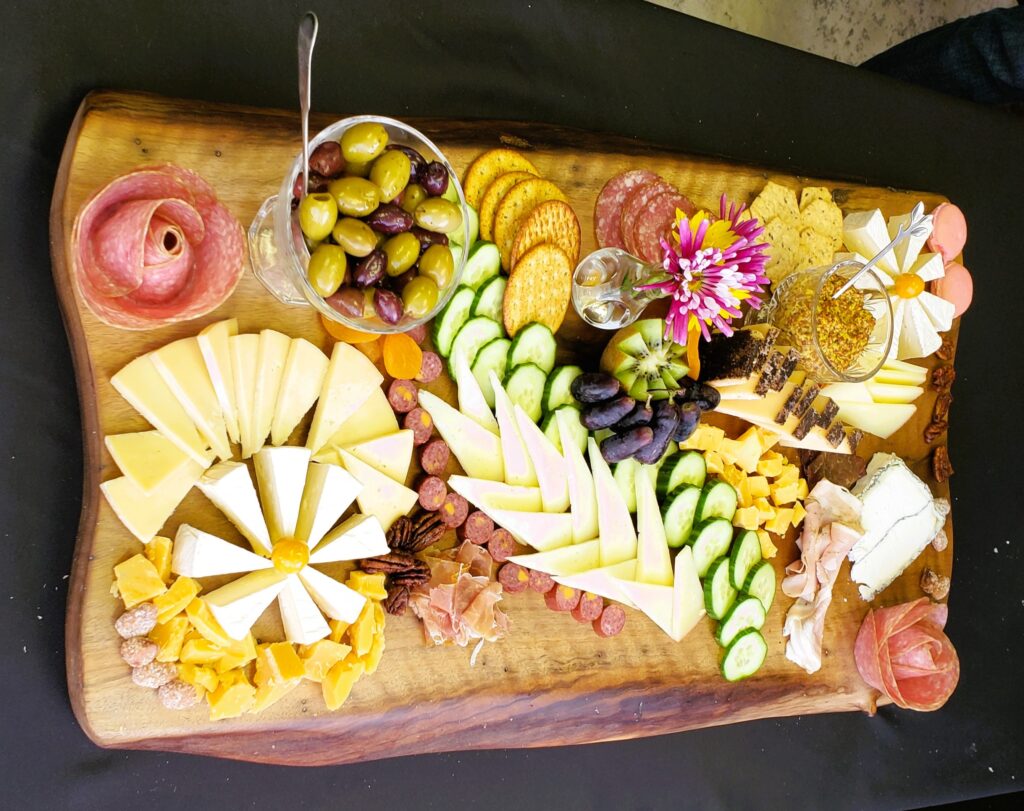 Charcuterie board filled with a variety of meats, cheeses, nuts, and even flowers