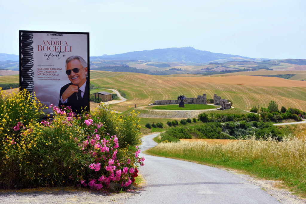 Poster announcing Andrea Bocelli in Tuscany at Teatro Del Silenzio Ampitheatre and the Teatro Del Silenzio in background in Tuscany, Italy