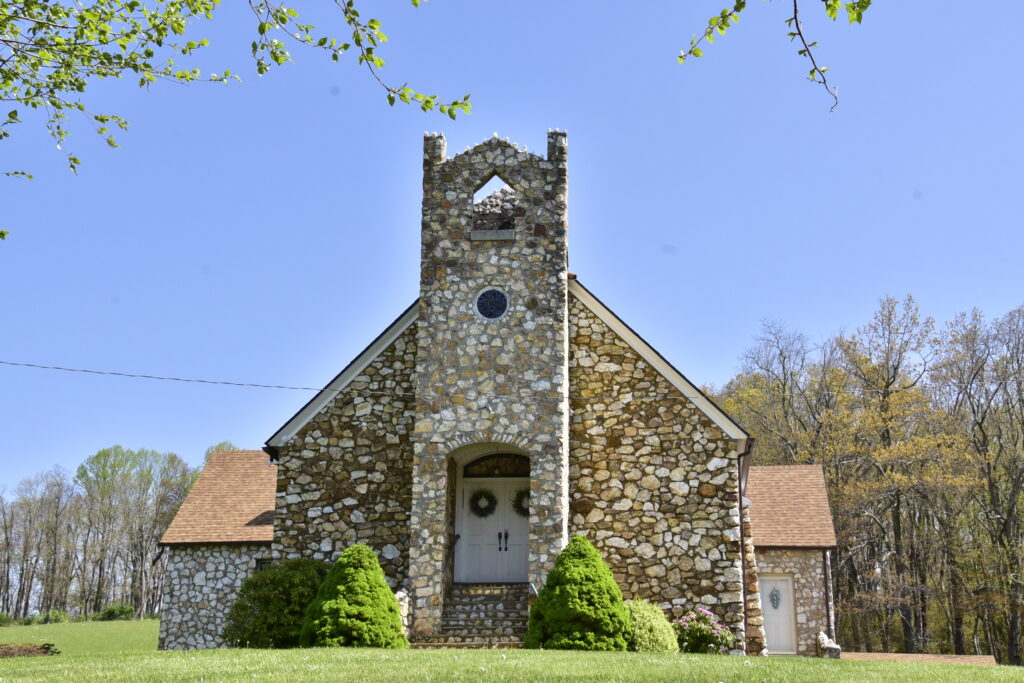 Beautiful fieldstone rock church in the mountains. White doors with wreaths.