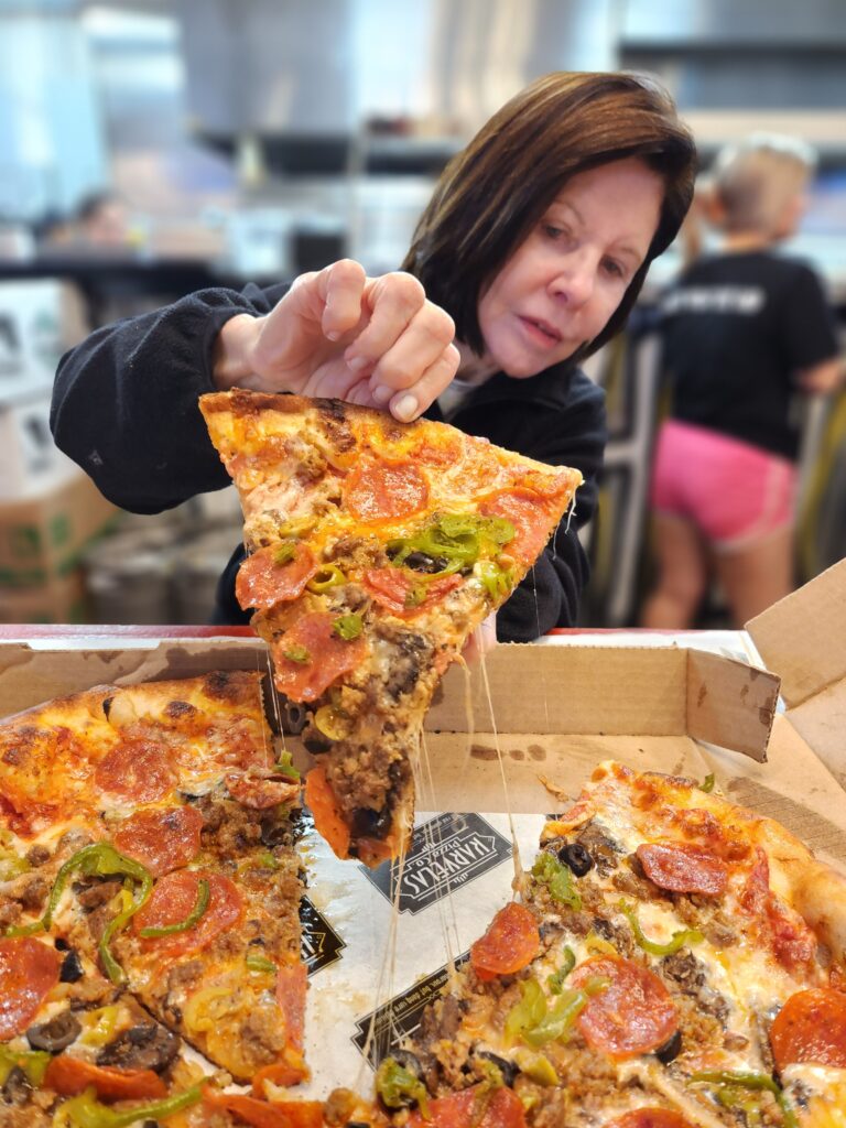 Woman holding slice of pizza and pulling up with the cheese stretching