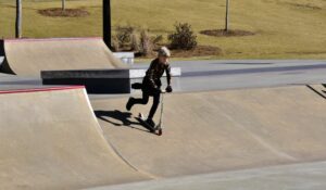Kid on a scooter riding down ramp at skate park