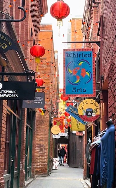 Fan Tan Alley, a narrow ally between tall brick buildings with red Chinese balloon lanterns hanging above the street