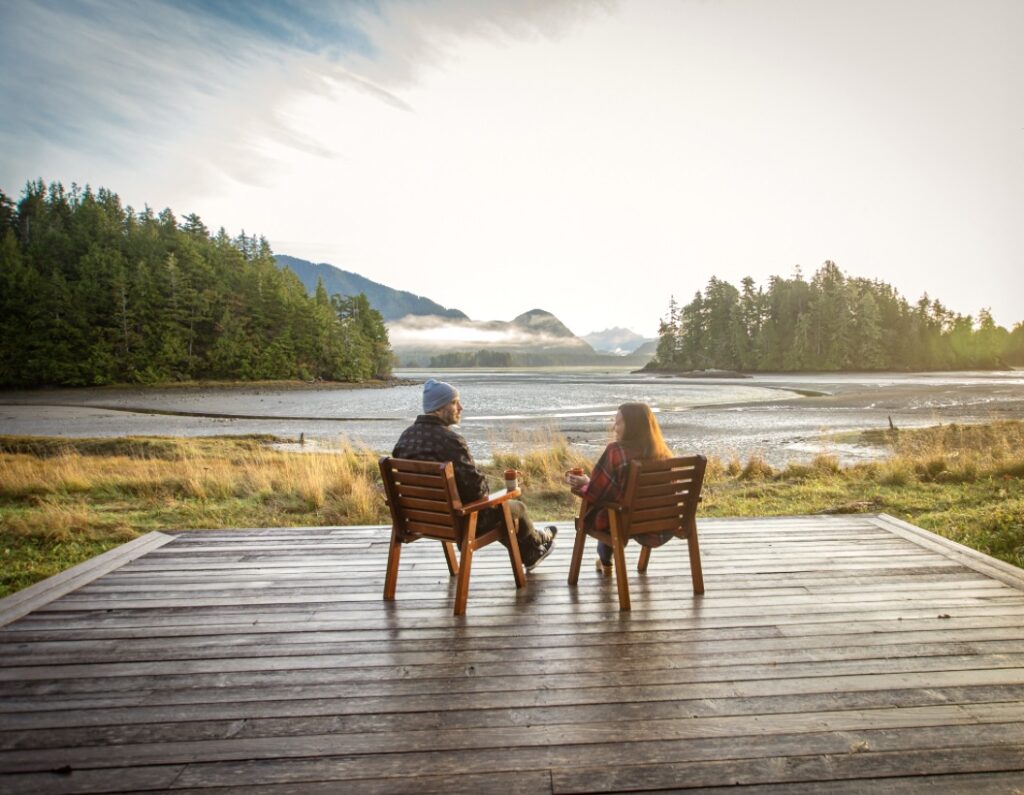 Couple sitting on deck overlooking water at the Bird Sanctuary at Hotel Zed, Tofino