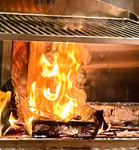Roaring fire at ROAR restaurant cooking mesh pan of food