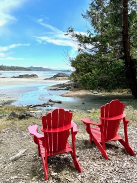 Red Adirondack chairs on Chesterman Beach overlooking the blue waters of the Pacific