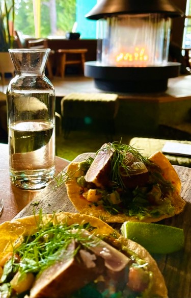 Tofino Tuna Tostada on a searving platter, with a caraf of white wine and fireplace in the background in Hotel Zed Sunken Living Room