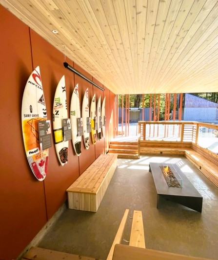 Outdoor deck with gas firepit, and benches. Surfboards hang on the wall at Tofino's Surf Grove
