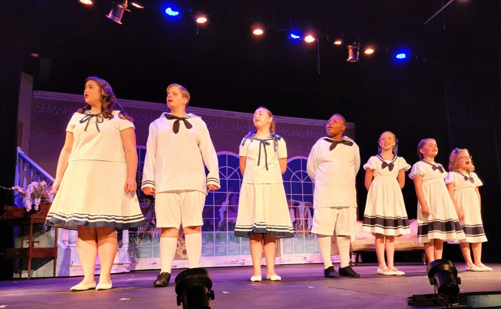 The Von Trapp Family children scene is on stage singing...7 children in white sailor costumes