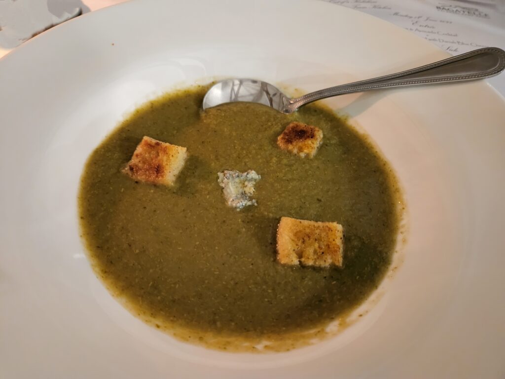 Broccoli Soup in a bowl topped with Danish Blue Cheese cubes.