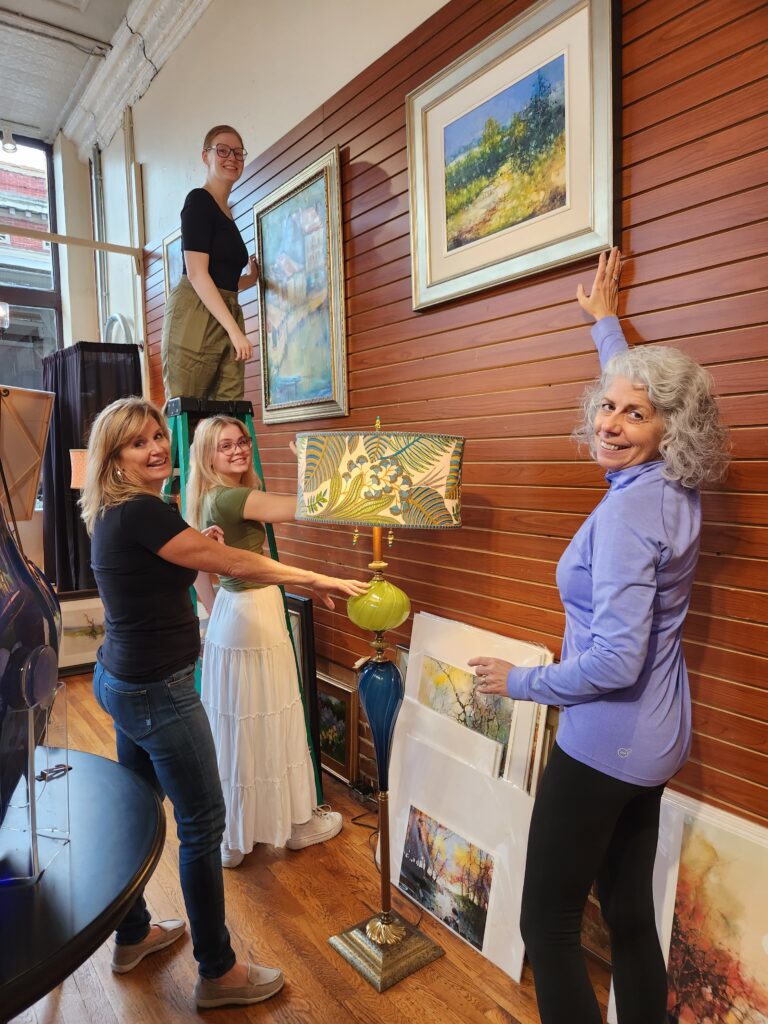 The women at an art store show off their wares.