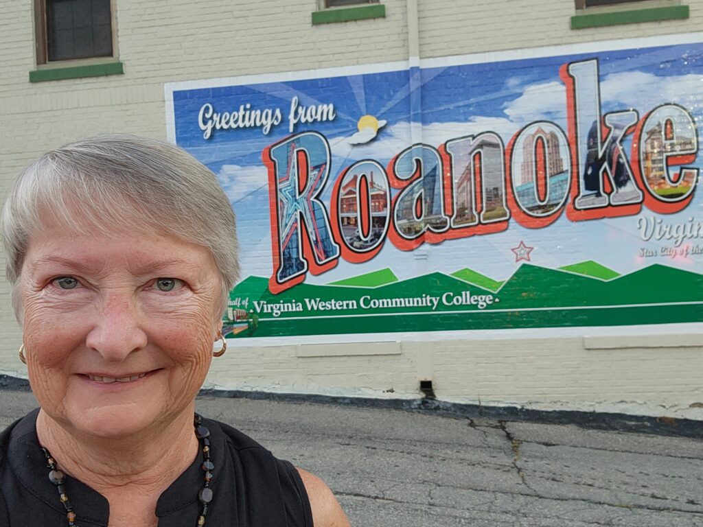 The author in from of a mural depicting a vintage "Greetings from Roanoke" postcard