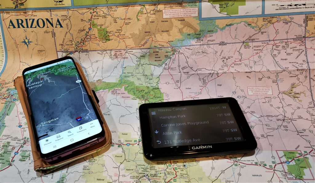 Arizona map lying on a table with a cell phone and Garmin GPS on top.