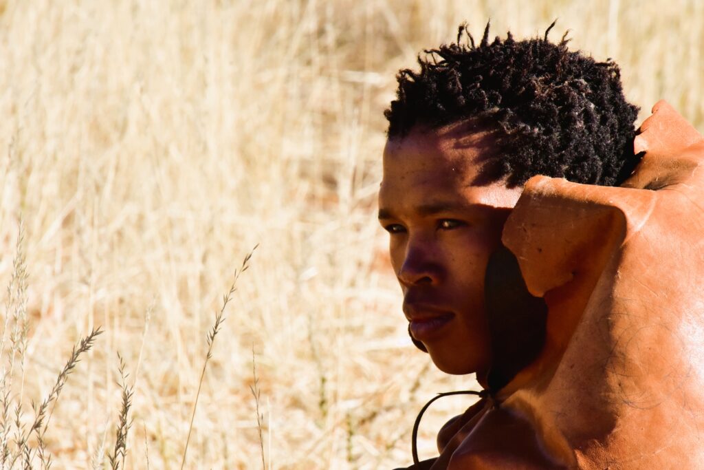 Closeup of a bushman sitting in the wild grass in Namibia.