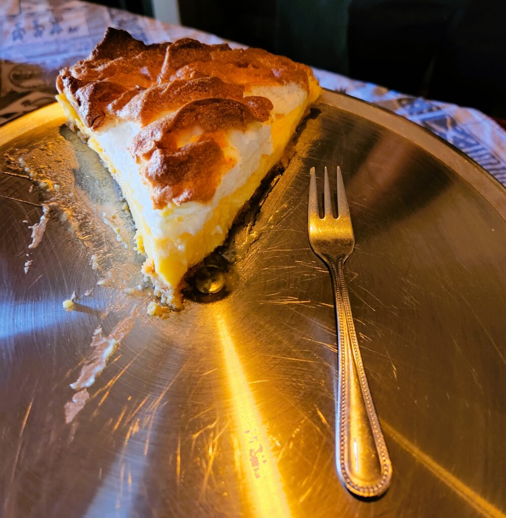 One slice of Lemon Pie on a stainless steel platter, piled high with meringue and toasted golden brown