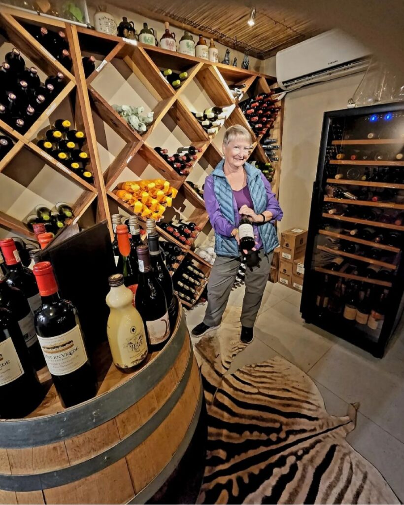 The author, Jo, holding a bottle of wine in a large wine cellar