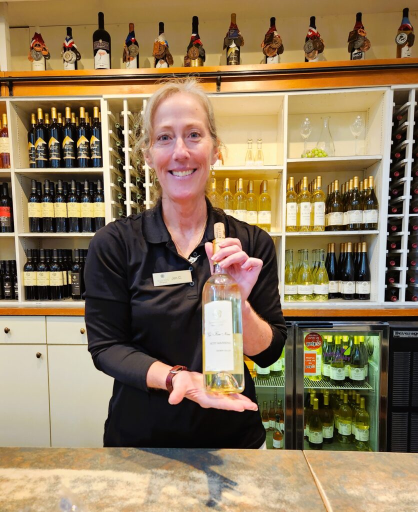 Jen, wearing a pleasant smile, happily pouring taste samples at Shelton Vineyard. 