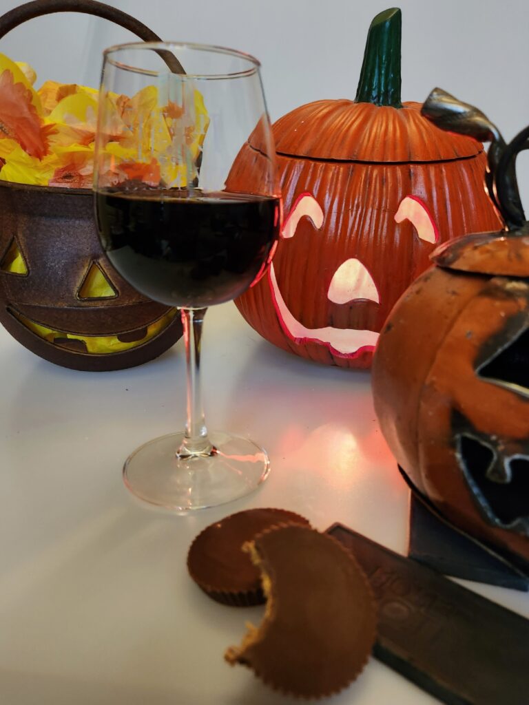 A wine goblet surrounded by jack-o-lanterns, but with a big bite missing from the Reese's cup!