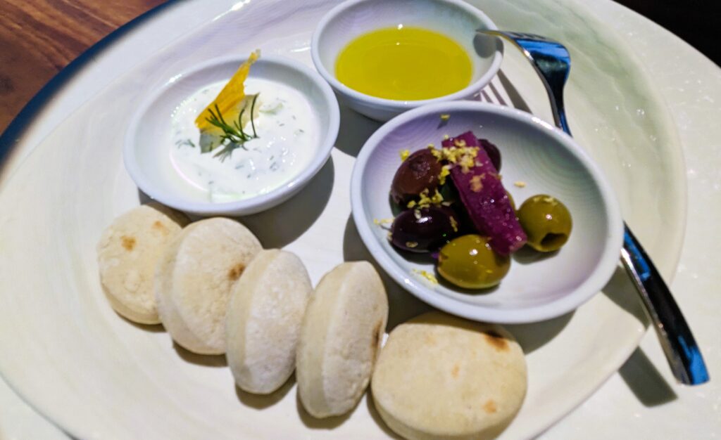 A beautiful plate of olives, pita rounds, and tzatziki to enjoy before dinner.