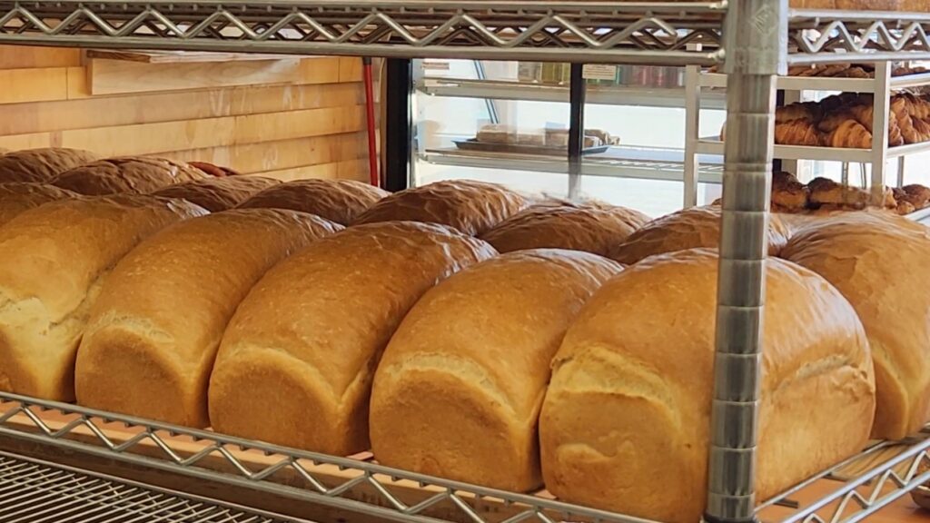Loaves of golden bread lined up on wire racks.