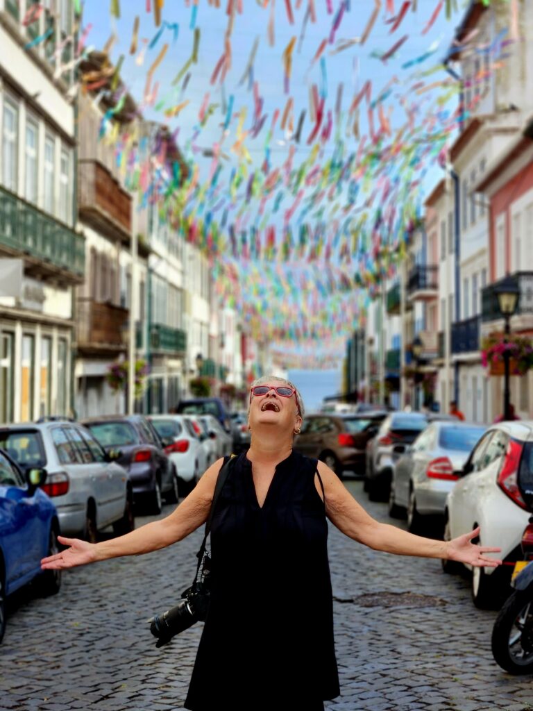 Author, Jo Clark, gazing up in delight at colorful streamers hanging from wires across the street
