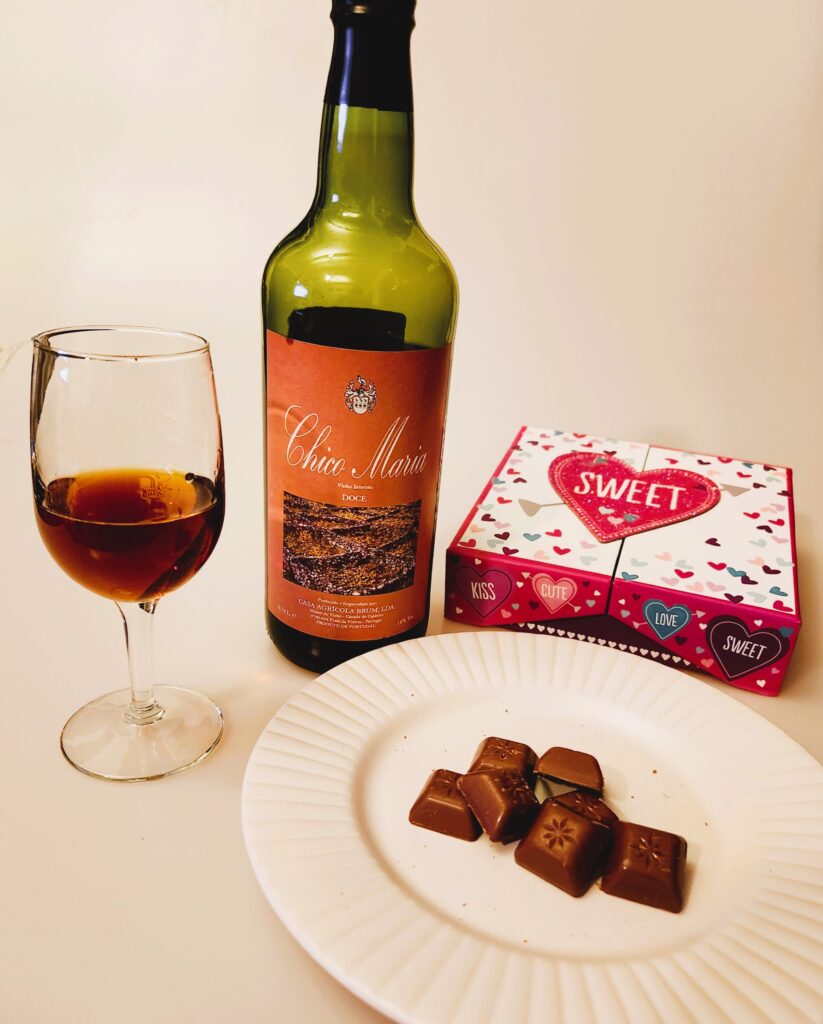 Wine and Chocolate would be the perfect gift for me. This photo shows bottle Chico Maria, a sweet wine from the Azores and handful of German Chocolates beside a wine glass of amber Portuguese wine, and a Valentine's Day Gift Box