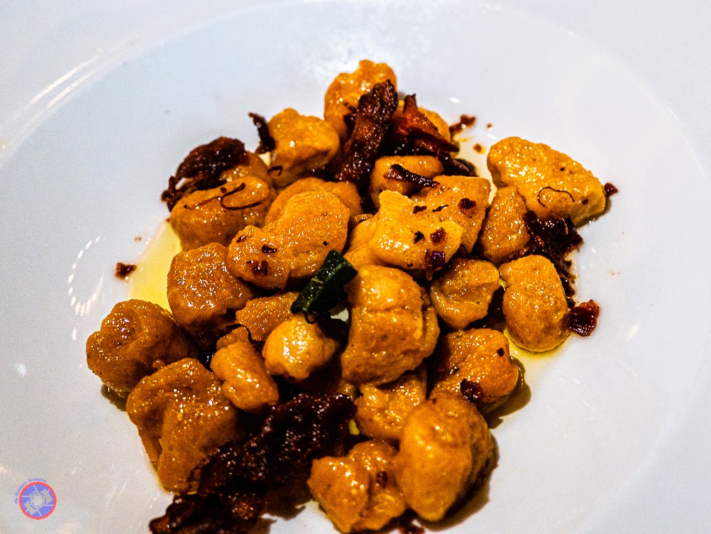 Special Food and Beverage Pairings - Up to the Hype? 100% 6 Beautiful orange pumpkin gnocchi is spread on a white plate and covered in sage brown butter for the main course of the food and beverage pairings dinner.