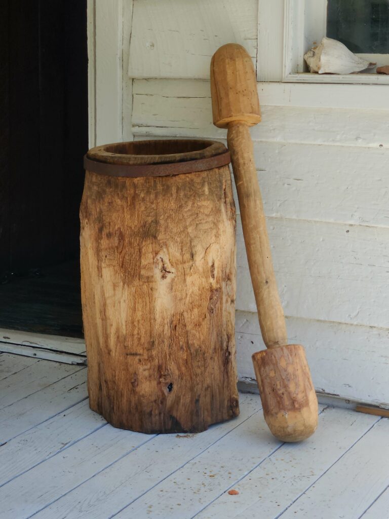 A carved wooden pestle and a bowl used as a mortar.