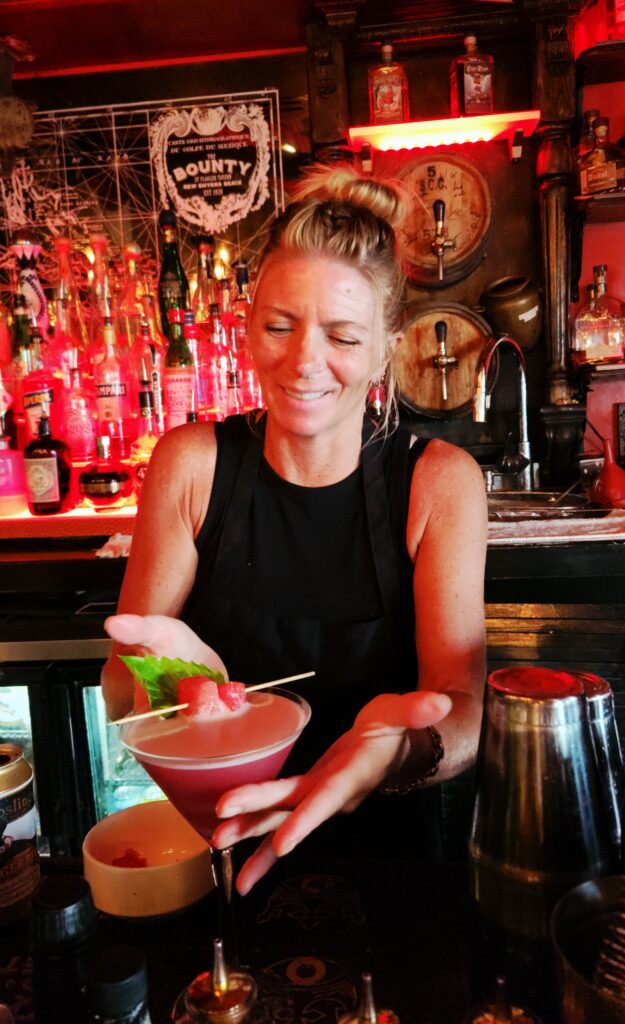 Ali, the Bounty's bartender, presents a red drink topped with a strawberry.