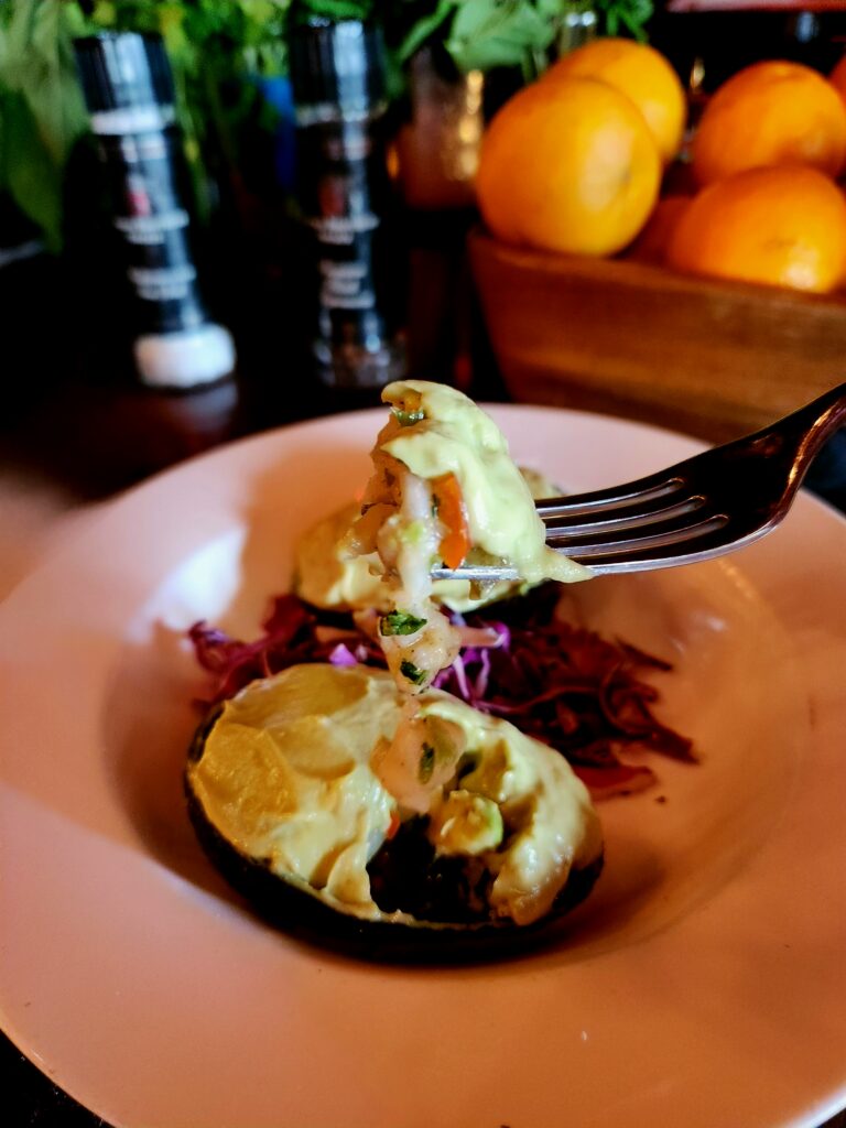 Ceviche Stuffed Avocado halves on top of red cabbage in a white bowl.