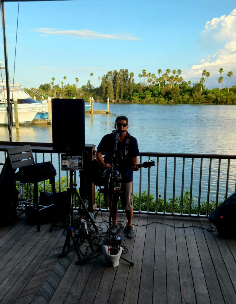 A musician playing on the dock at Outriggers Tiki Bar and Grille.